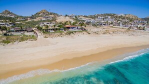 A coastal area with a beach, clear turquoise waters, and a hillside with residential buildings. - Your Dream Beach Getaway Awaits, San Jose Del Cabo 1022 (San Jose Del Cabo)