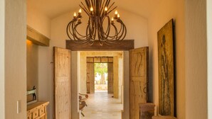 A hallway with wooden doors, a stone pillar, and a large painting on the wall. - Your Dream Beach Getaway Awaits, San Jose Del Cabo 1022 (San Jose Del Cabo)