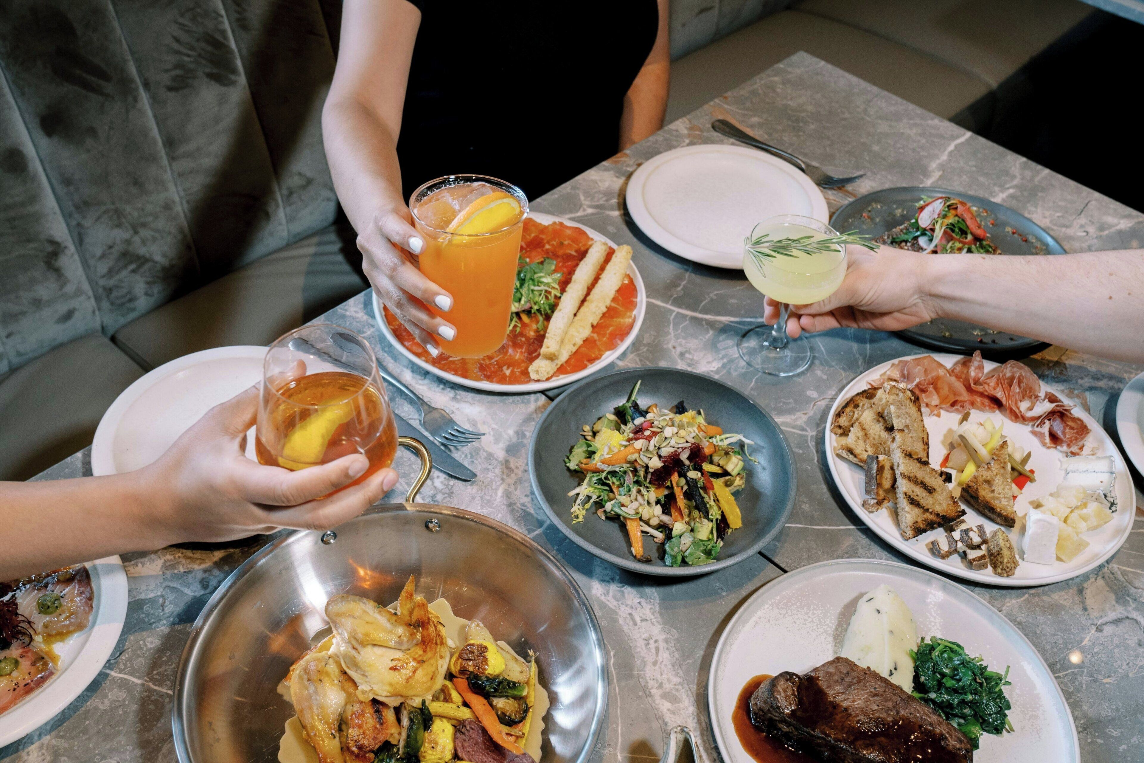 Uma mesa de jantar com diversos pratos, incluindo uma salada, frango assado e um prato de carne.