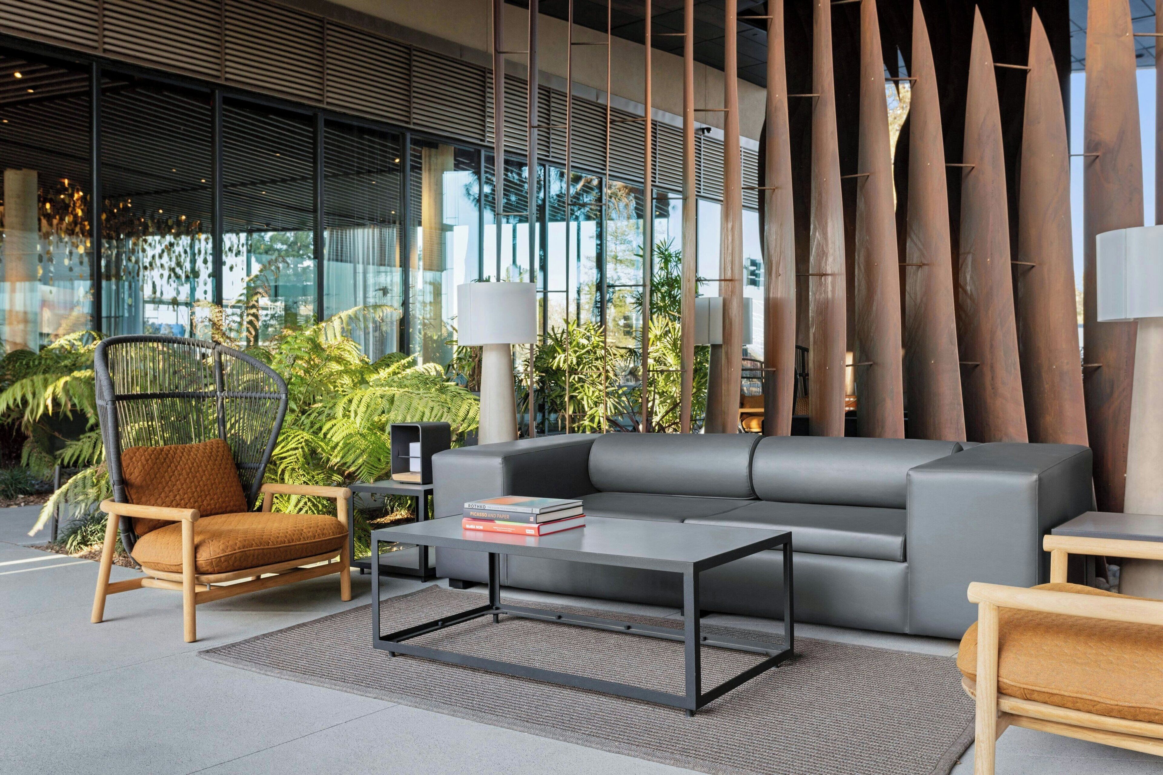A modern indoor space with a grey sofa, a wooden chair, and a coffee table.