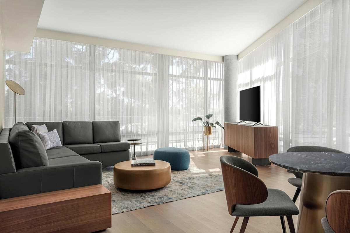 A modern living room with a sectional sofa, round coffee table, and a dining area with a table and chairs.