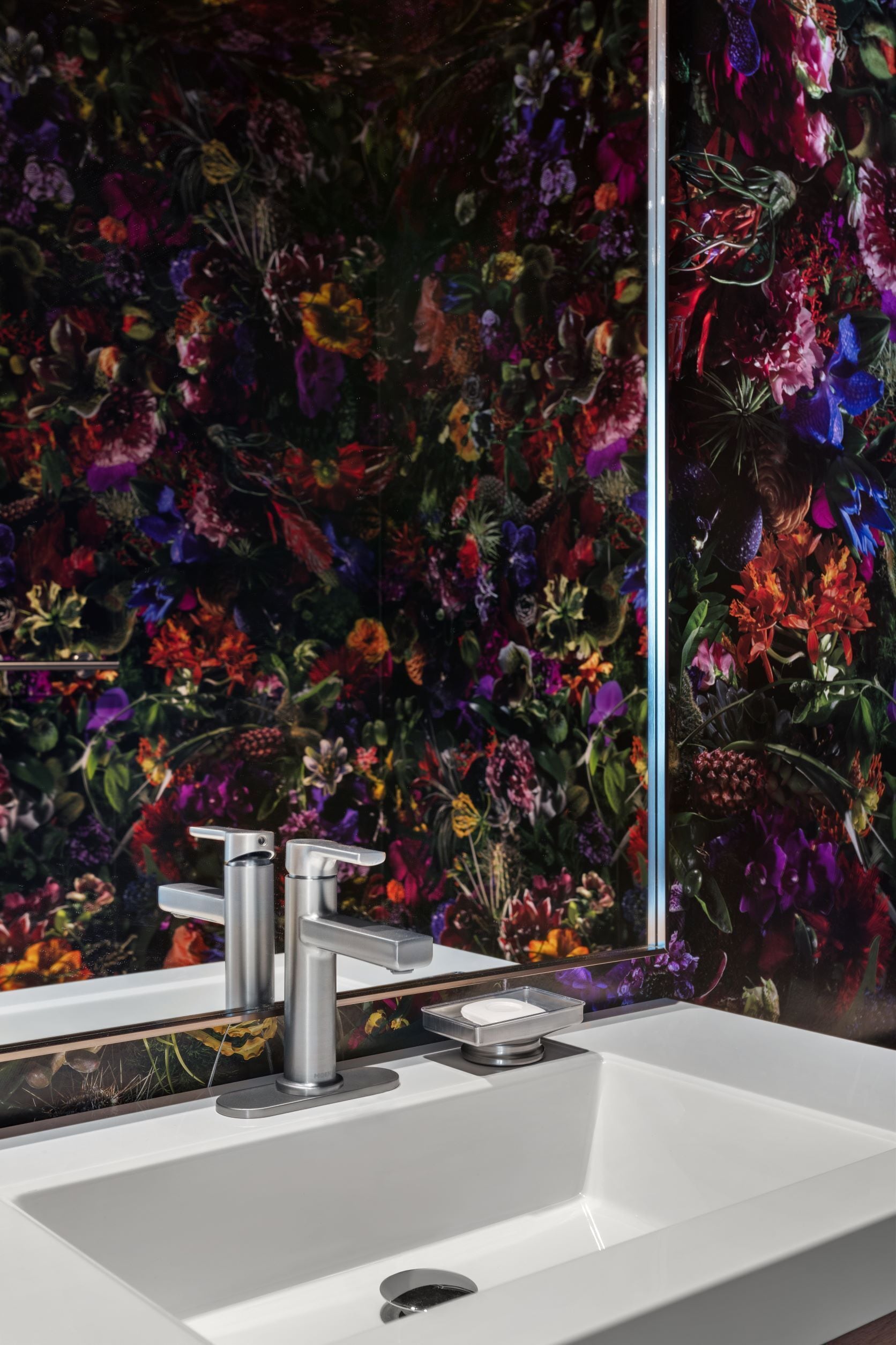 A bathroom with a white sink, a modern faucet, and a mirror.