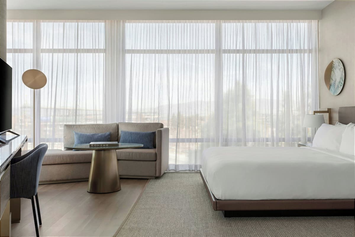 A hotel room with a large bed, a sofa, a small table, and a TV.