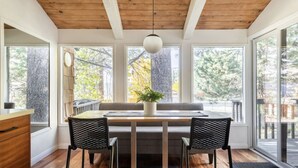 A dining area with a wooden table, two chairs, a bench, and a hanging light fixture.
