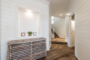 A hallway with a wooden bench, a staircase, and a wall-mounted shelf with decorative items. - Sunset Island 53 Island Edge Drive (Ocean City)