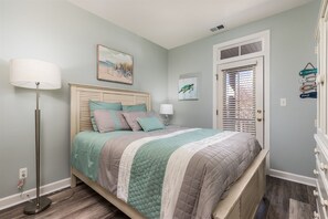 A bedroom with a bed, bedside lamps, a floor lamp, a door with a window, and wall decorations.