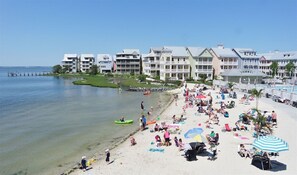 Een strand met een rij gebouwen, helder water en mensen die ontspannen op het zand.