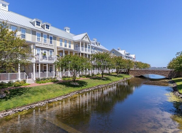 A row of waterfront hotel buildings with balconies, a stone bridge, and a calm river.