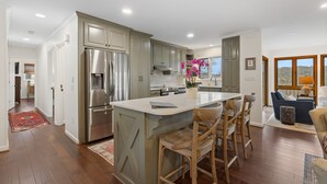 A spacious kitchen with a central island, stainless steel appliances, and wooden bar stools. - Charming newly renovated cottage, incredible mountain views, walk to town (Highlands)