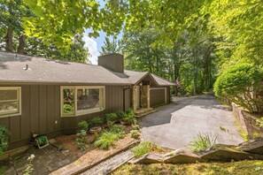 A residential property with a garage, a covered porch, and a driveway leading to a road. - Charming newly renovated cottage, incredible mountain views, walk to town (Highlands)