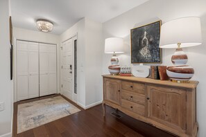 A hallway with a wooden cabinet, two lamps, a rug, and a door. - Charming newly renovated cottage, incredible mountain views, walk to town (Highlands)