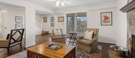Un salon spacieux avec une table basse en bois, deux fauteuils, un tapis à motifs et une cheminée en pierre.
