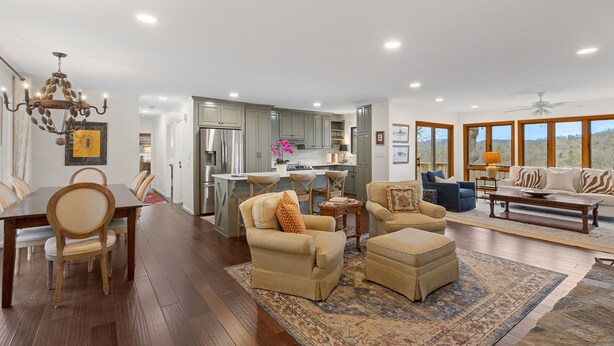 A spacious living area with a dining table, comfortable seating, a kitchen, and large windows offering a view. - Charming newly renovated cottage, incredible mountain views, walk to town (Highlands)