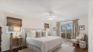 A bedroom with a large bed, a bedside table with a lamp, a chair, and a view of the outdoors. - Charming newly renovated cottage, incredible mountain views, walk to town (Highlands)
