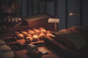 Une vitrine de boulangerie présentant diverses sortes de pains et de viennoiseries, une pancarte indiquant « pain de mie », et un comptoir en bois.