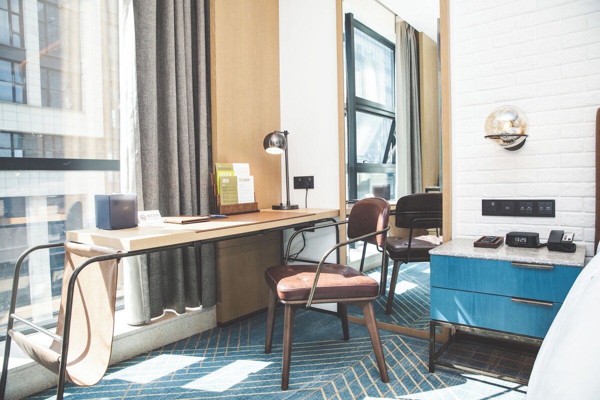 Une chambre d’hôtel avec un bureau, une chaise et un placard bleu.