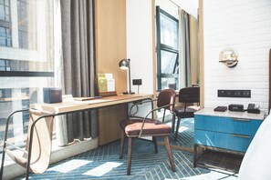 Une chambre d’hôtel avec un bureau, une chaise et un placard bleu.