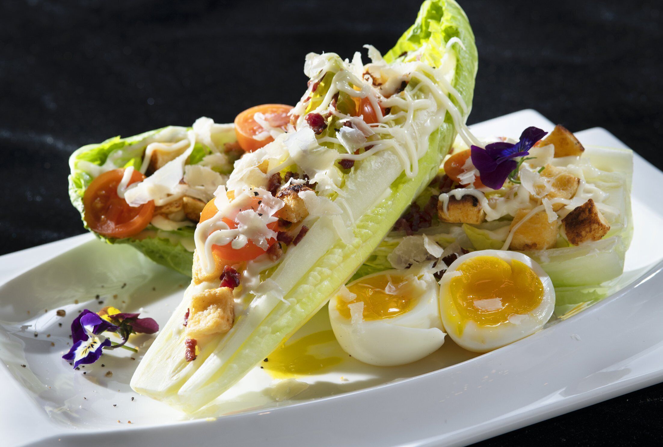 Salada com alface, tomate, ovos e croutons em um prato branco.