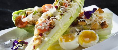 Salada com alface, tomate, ovos e croutons em um prato branco.