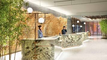 A modern reception area with a bamboo wall, marble counters, and a glass partition.