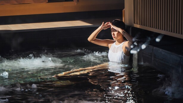 A person in a white tank top sitting in a hot tub with steam rising from the water. - Crowne Plaza Beijing Badaling by IHG (Yanqing)