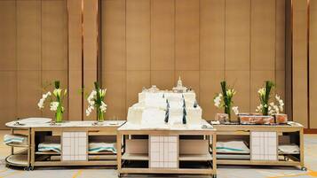 A reception area with a reception desk, a model of a building, and two flower arrangements.
