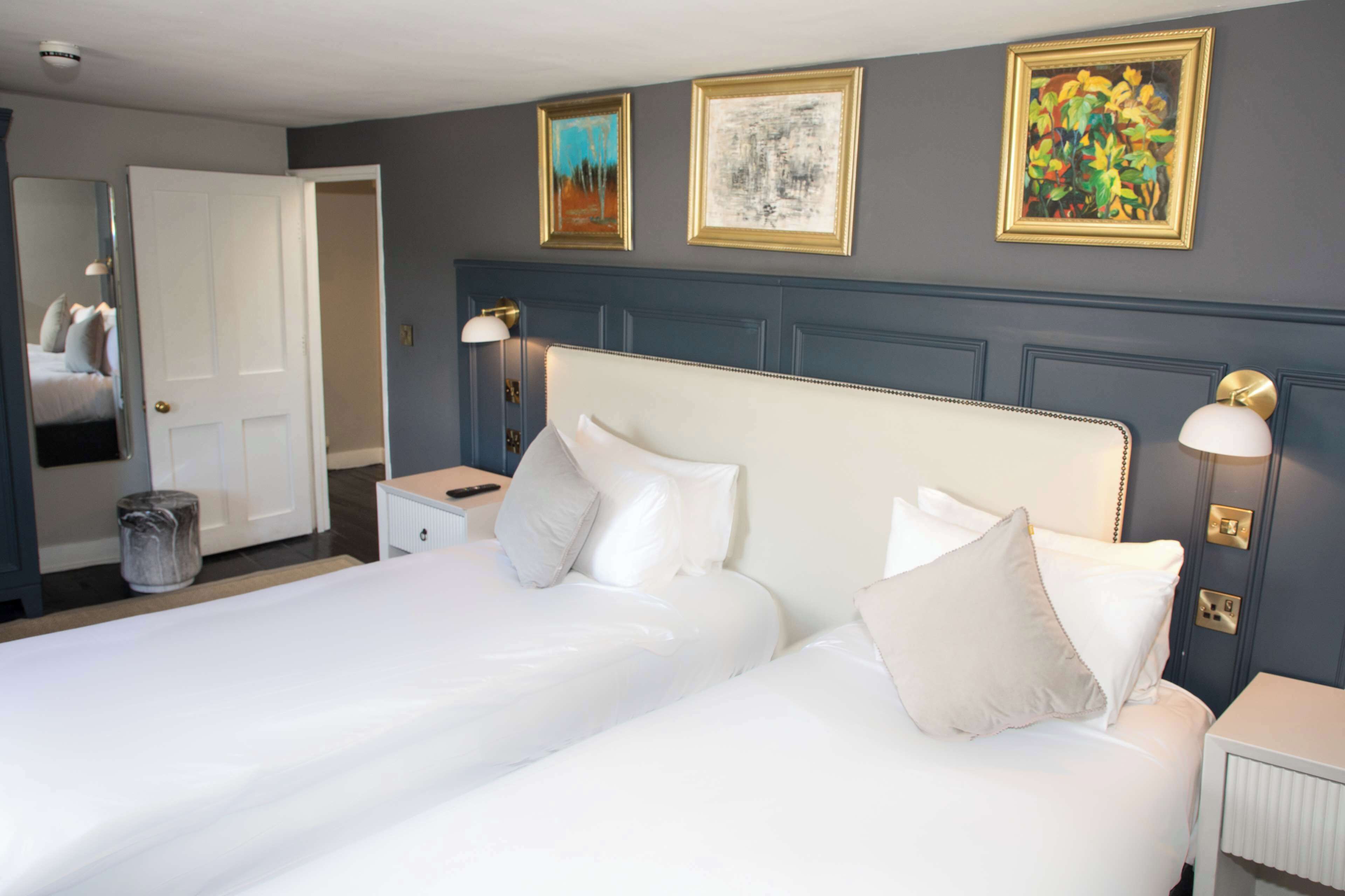Une chambre d’hôtel avec deux lits, une table de chevet, une lampe et un miroir.