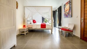 A bedroom with a bed, nightstand, chair, and artwork on the wall. - Rent a Luxury Villa in Bali Close to the Beach, Bali Villa 2057 (Bali)