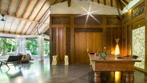 A spacious room with a high ceiling, a wooden table with decorative items, and a view of lush greenery outside. - 5 Star Villa in Bali, Minutes from the Beach, Bali Villa 2065 (Bali)