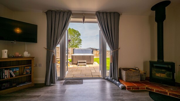 Una sala de estar con televisor, estantería, chimenea y vista al jardín.