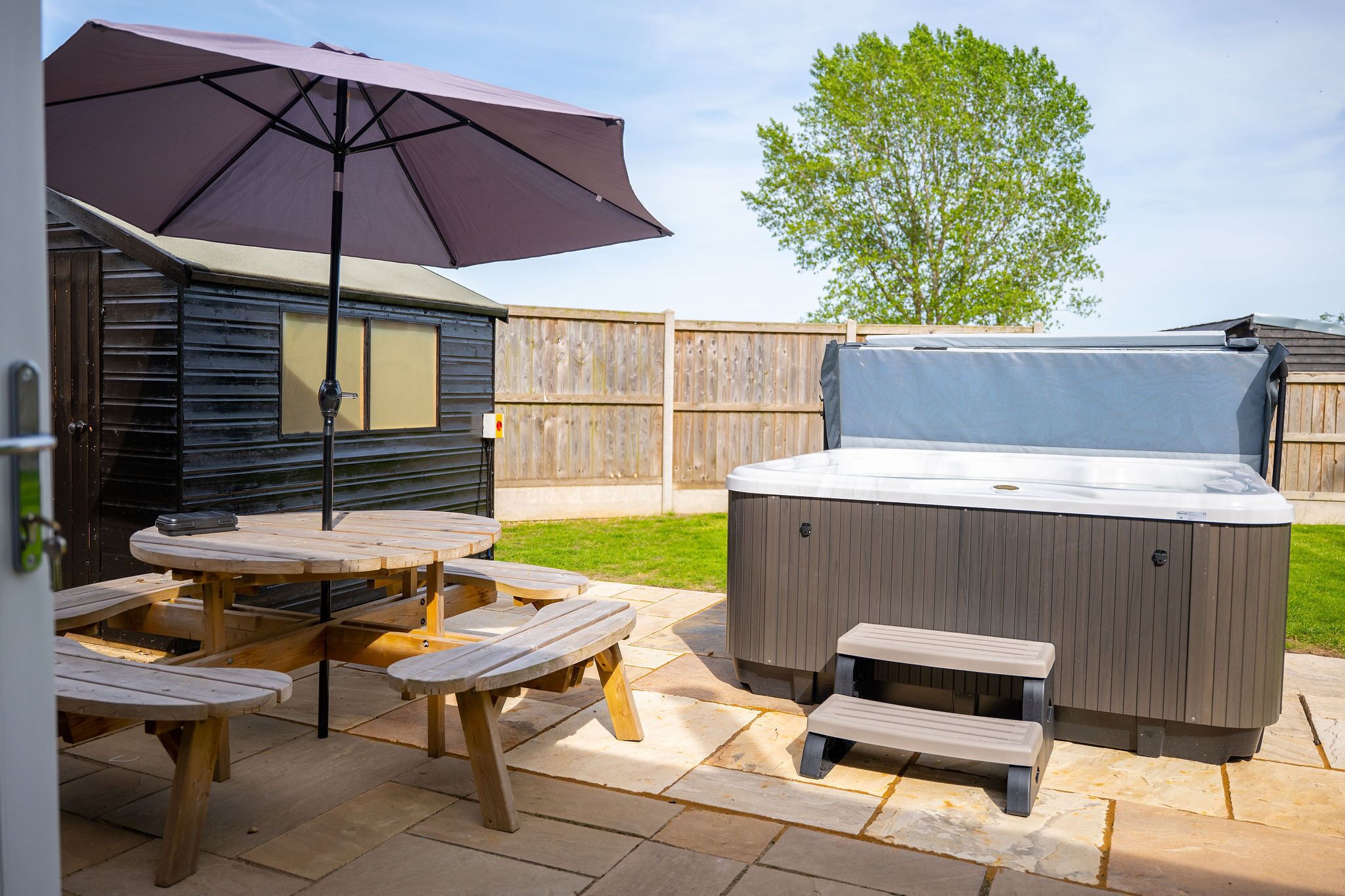 A patio area with picnic tables and a hot tub.