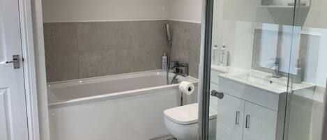 A modern bathroom with a glass-enclosed shower, a bathtub, and a toilet.