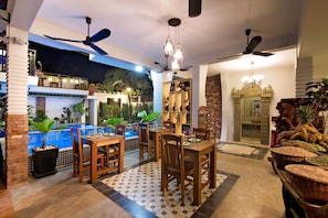 A dining area with a pool, ceiling fans, and a chandelier.