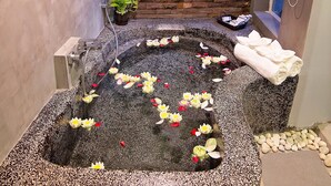 A spa area with a stone hot tub, a potted plant, and towels on a bench. - Damnak Villa Boutique (Siem Reap)