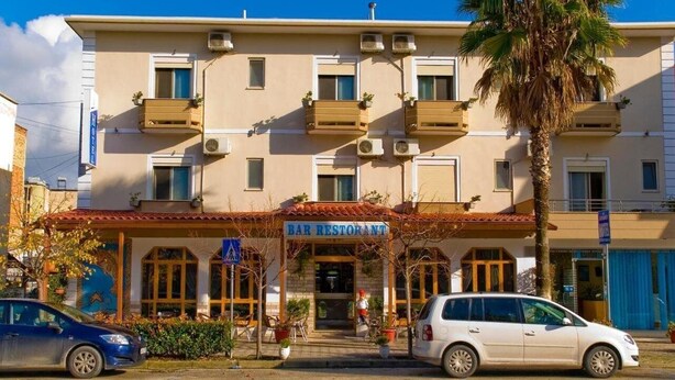 A two-story building with a bar restaurant on the ground floor. There are two cars parked in front. - 4 Stinet Hotel (Vlorë)