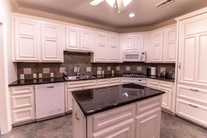 A kitchen with white cabinetry, a black countertop, a dishwasher, and a microwave.