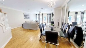 Un vaste espace de vie comprenant une table à manger, des chaises, un canapé et un lustre.