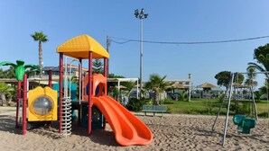 Un parque infantil en la playa con un tobogán y estructuras para escalar.