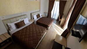 Habitación de hotel con dos camas, un televisor, un teléfono y una mesita.