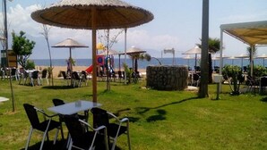 Un espacio al aire libre con mesas y sillas, sombrillas y vistas a la playa.