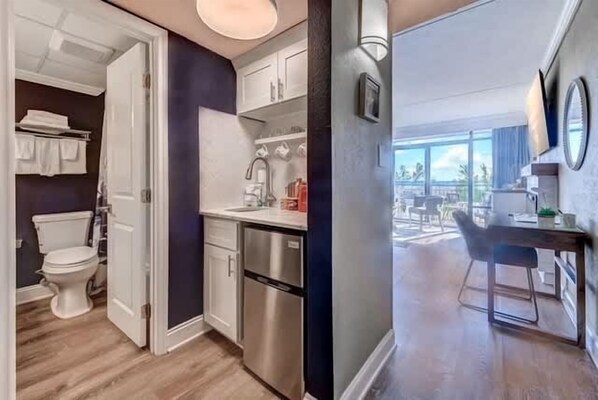 A modern kitchen with stainless steel appliances, a dining area with a table and chairs, and a view through large windows. - Grande Cayman 124 (Myrtle Beach)