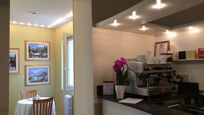 A restaurant interior with a dining area, a coffee machine, and framed pictures on the wall. - Basilica Hotel (Rome)