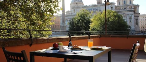 A balcony with a table set for breakfast, overlooking a historic building with domes.
