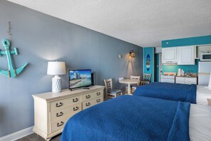 A hotel room with two beds, a dresser, a television, a lamp, a small table, and a kitchenette. - Tides 20908 - Gorgeous Oceanfront Views for 4! (Myrtle Beach)