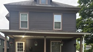 A two-story house with a covered porch, a front door, and a small window on the second floor. - 3 bedroom/1.5 bath Baseball rental 6 minutes to Cooperstown All star village.  (Oneonta)