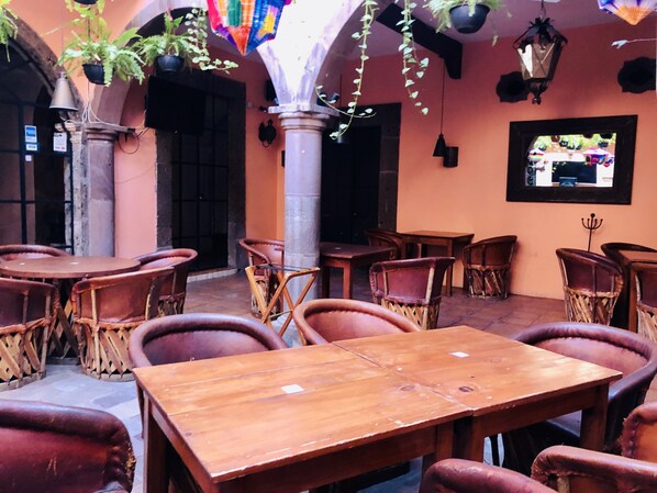 A restaurant with wooden tables and chairs, hanging plants, and a mural on the wall. - Hotel Mansión Virreyes (San Miguel de Allende)