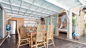 A wooden dining table with chairs, a water dispenser, and a refrigerator in the background.