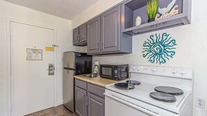 A compact kitchen with a refrigerator, microwave, stove, and a decorative wall piece. - Sea Mist 51610 (Myrtle Beach)