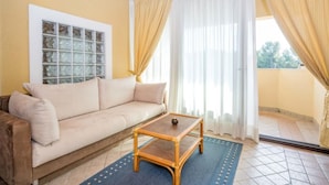 A living room with a beige sofa, a wooden coffee table, and a view through a glass door. - VILLA ROSSELLA 1 Two-Bedroom Apartment (Prunella) (Rovinj)