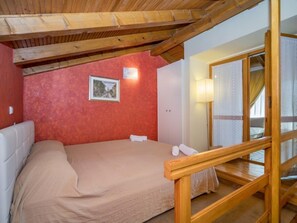 A bedroom with a wooden ceiling, a bed with a beige bedspread, a framed picture on the wall, and a bedside lamp. - VILLA ROSSELLA 1 Two-Bedroom Apartment (Prunella) (Rovinj)